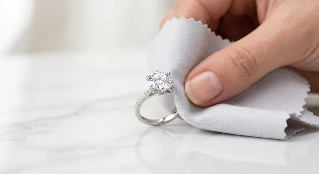 Gloved hands cleaning a ring with a soft cloth before a shoot